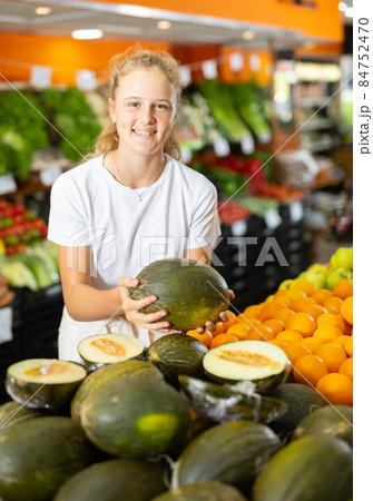 Smiling fifteen-year-old girl chooses a melon Smiling fifteen-year-old girl chooses a melon 84752470