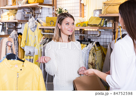 Two young women friends talking in fashion clothes shop Two young women friends talking in fashion clothes shop 84752598