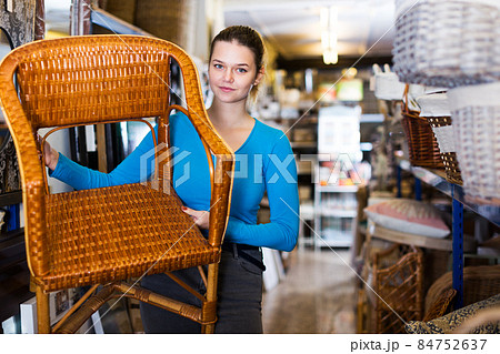woman standing with wicker chair in shop for decor woman standing with wicker chair in shop for decor 84752637