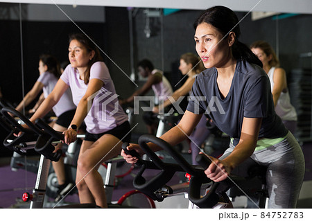 Woman ride stationary bike in fitness club Woman ride stationary bike in fitness club 84752783