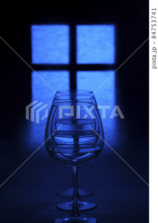 Still life with glass goblets with liquid against the background of a glowing window silhouette Still life with glass goblets with liquid against the background of a glowing window silhouette 84753741