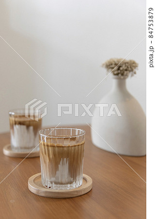 Iced dirty latte coffee in vintage decoration of wooden table with modern vase. Iced dirty latte coffee in vintage decoration of wooden table with modern vase. 84753879