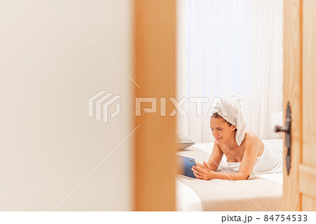 A smiling woman wrapped in towels using her digital tablet. A smiling woman wrapped in towels using her digital tablet. 84754533
