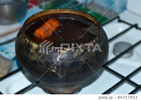 Dark-colored cast iron pot with vegetables. 84757933