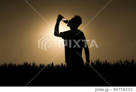 Silhouette of man at sunset, man drinks a water. Silhouette of man at sunset, man drinks a water. 84758252