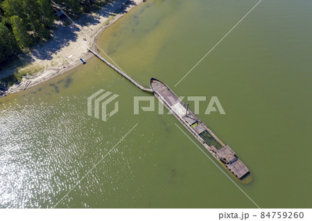 Aerial view of half-sunken rusty barge at the last berth on Ob River in Siberia, Russia, in summer Aerial view of half-sunken rusty barge at the last berth on Ob River in Siberia, Russia, in summer 84759260