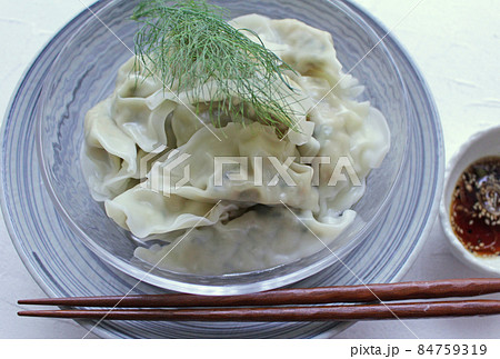 透明ガラスの丸皿に盛った涼し気な水餃子と餃子のたれ 84759319