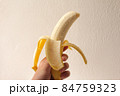 コピースペースがある白いバックの背景の皮をむいたバナナを持つ手 84759323