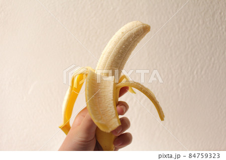 コピースペースがある白いバックの背景の皮をむいたバナナを持つ手 コピースペースがある白いバックの背景の皮をむいたバナナを持つ手 84759323