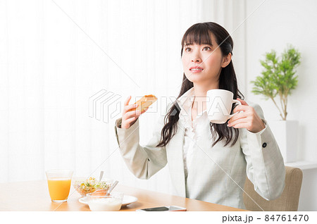 出勤前に朝食を摂りながら時間を気にする女性 84761470