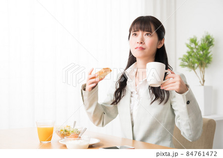 出勤前に朝食を摂りながら時間を気にする女性 84761472