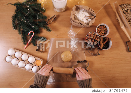 Woman using rolling pin for making gingerbread. Top view of rolling raw dough for gingerbread. Christmas mood. Preparing for hollidays 84761475