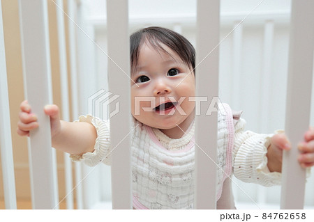 つかまり立ちをする生後半年の赤ちゃんの女の子 84762658