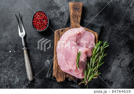 Fresh Raw whole big turkey breast fillet on wooden board. Black background. Top View Fresh Raw whole big turkey breast fillet on wooden board. Black background. Top View 84764639