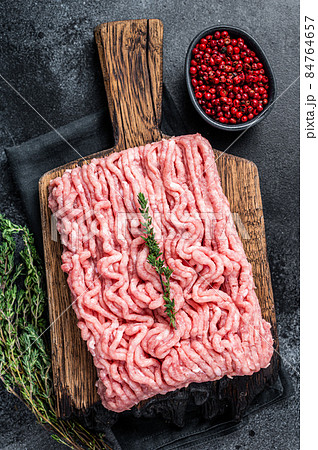 Ground chicken or turkey raw meat on wooden board. Black background. Top View 84764657
