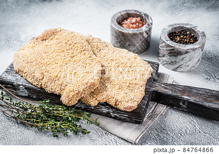 Wiener Raw schnitzel in breadcrumbs on wooden board. White background. Top view 84764866