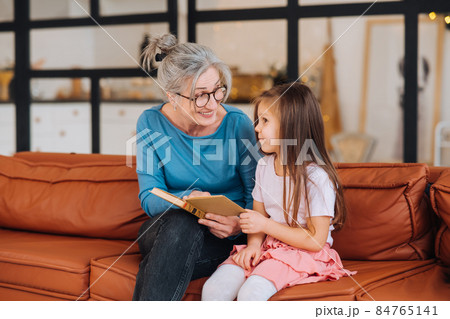 Nice elderly woman grandmother reading story to granddaughter. 84765141