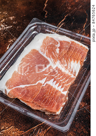 Italian prosciutto crudo or jamon in a vacuum package. Dark background. Top View 84765624