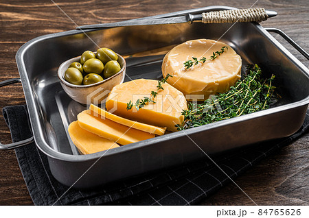 Fresh Halloumi sliced cheese in kitchen tray with thyme. Wooden background. Top view 84765626