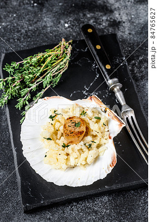 Risotto with pan seared sea scallops in a shell. Black background. Top view 84765627
