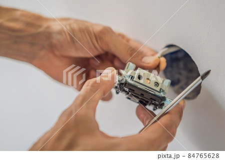 Master electrician installs a socket in the house 84765628