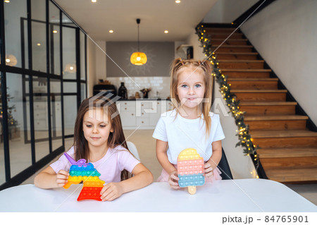 Photo of two little girls playing at the table on the camera 84765901