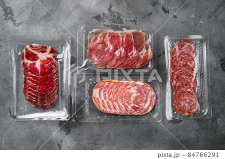 Vacuum packed sausage Prosciutto salami, on gray stone table background, top view flat lay, with copy space for text 84766291