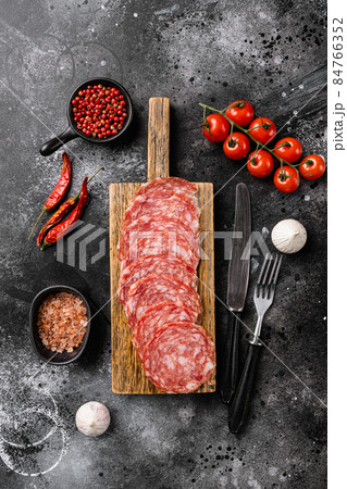 Traditional dry cured Milano salami, on black dark stone table background, top view flat lay Traditional dry cured Milano salami, on black dark stone table background, top view flat lay 84766352