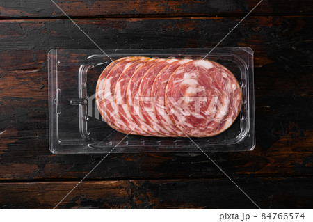 Jamon Serrano traditional Spanish cuisine cured pork meat pack, on old dark wooden table background, top view flat lay, with copy space for text 84766574