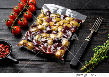 Olives in vacuum packaging for supermarket, on black wooden table background 84766609