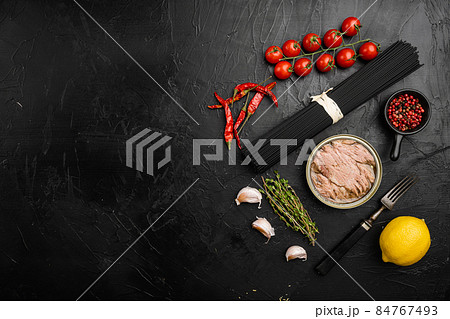 Pasta with tuna raw ingredients, on black dark stone table background, top view flat lay, with copy space for text 84767493