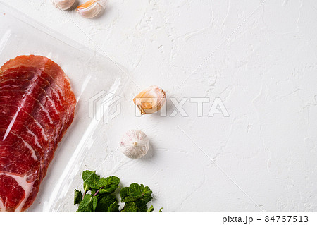 Italian dry cured ham vacuum pack, on white stone table background, top view flat lay, with copy space for text 84767513