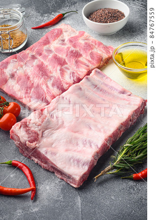 Fresh rack of raw pork spare ribs seasoned with spices, on gray background Fresh rack of raw pork spare ribs seasoned with spices, on gray background 84767559