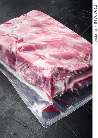 Raw pork ribs vacuum packed, on black stone background, with copy space for text Raw pork ribs vacuum packed, on black stone background, with copy space for text 84767612