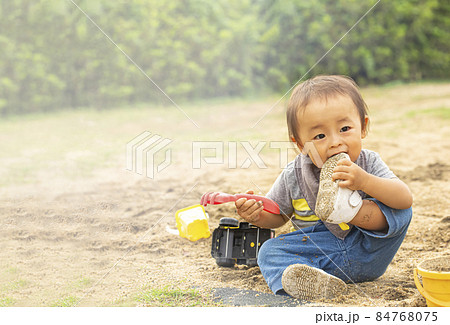 砂場で遊びながら 自分の履いている靴に噛みつく男の子 汚れた靴を口に入れるの写真素材 砂場で遊びながら 自分の履いている靴に噛みつく男の子 汚れた靴を口に入れるの写真素材