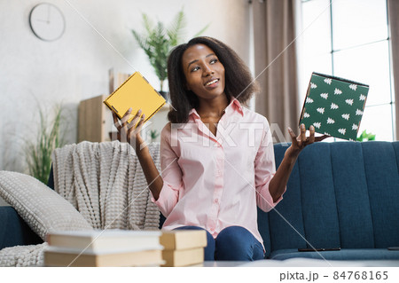 Pleasant woman sitting on couch with gift boxes in hands Pleasant woman sitting on couch with gift boxes in hands 84768165