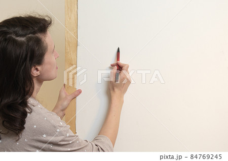 The artist draws with pencil on a white canvas. View from behind the shoulder. Drawing with watercolors in a home art studio. 84769245