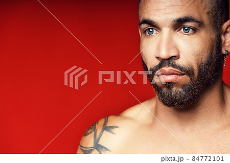 Face with a beard and an earring in the ear of a Cuban man close-up. Studio portrait of a brutal man 84772101