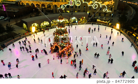 people skate on ice rink around christmas tree 84772900
