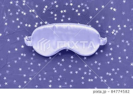 Color of the year 2022 very peri. Trendy colors concept. Satin eye sleeping mask and silver stars confetti on dark black background. Sweet dreams concept. Copy space, flat lay. Accessories for women 84774582
