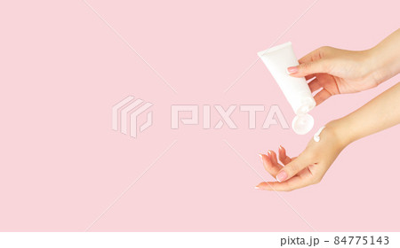 Hand with cosmetic skincare moisturizer cream tube on pink background 84775143