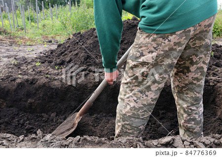 Man digs a deep pit. Digging a pit by shovel. Man digs a deep pit. Digging a pit by shovel. 84776369