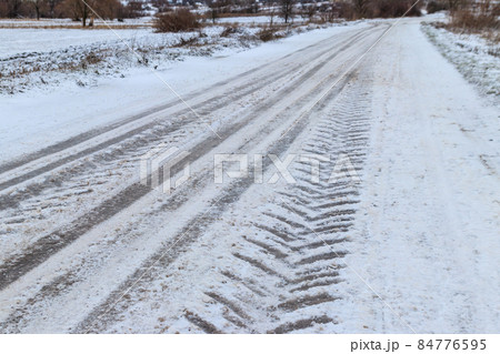 Tire tracks on icy road covered with snow 84776595