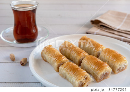 Baklava and Turkish tea. Crispy pistachio baklava on a white plate. 84777295