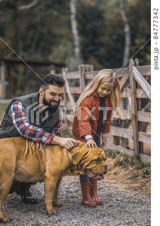 Farmer and his daughter caressing their dog 84777342