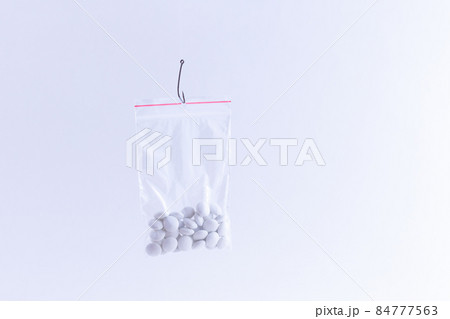 White Pills or Tablets Hanging in Small Ziplock Bag on a Fishing Hook White Pills or Tablets Hanging in Small Ziplock Bag on a Fishing Hook 84777563