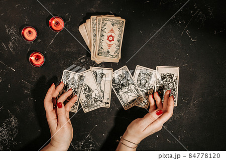 Tarot cards and female hands of fortune teller on black magic table Tarot cards and female hands of fortune teller on black magic table 84778120
