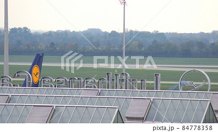 MUNICH, GERMANY - 11 OCTOBER 2015: View of the Munich Airport MUC terminal building with an airplane in background 84778358