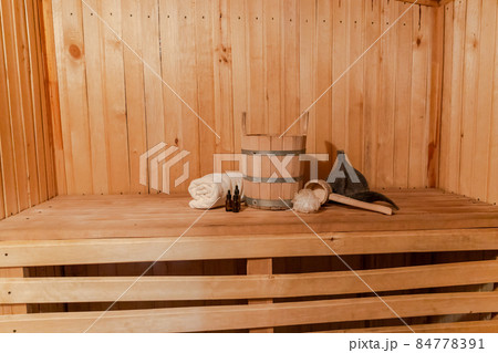 Traditional old Russian bathhouse SPA Concept. Interior details Finnish sauna steam room with traditional sauna accessories set basin towel aroma oil scoop felt. Relax country village bath concept 84778391