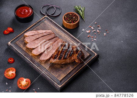 Cooked grilled Chuck eye roll steak on a chopping Board 84778526